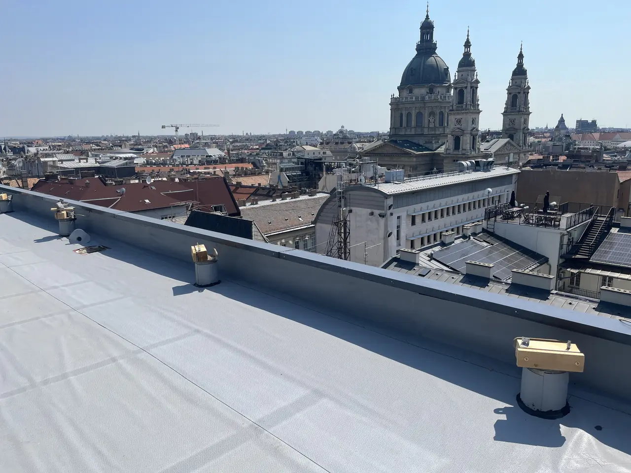 Szürke PVC lemezzel szigetelt belvárosi lapostető, a háttérben a Szent István-bazilika