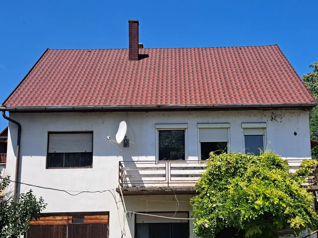 Új piros tetőfedés egy kétszintes, erkélyes családi házon