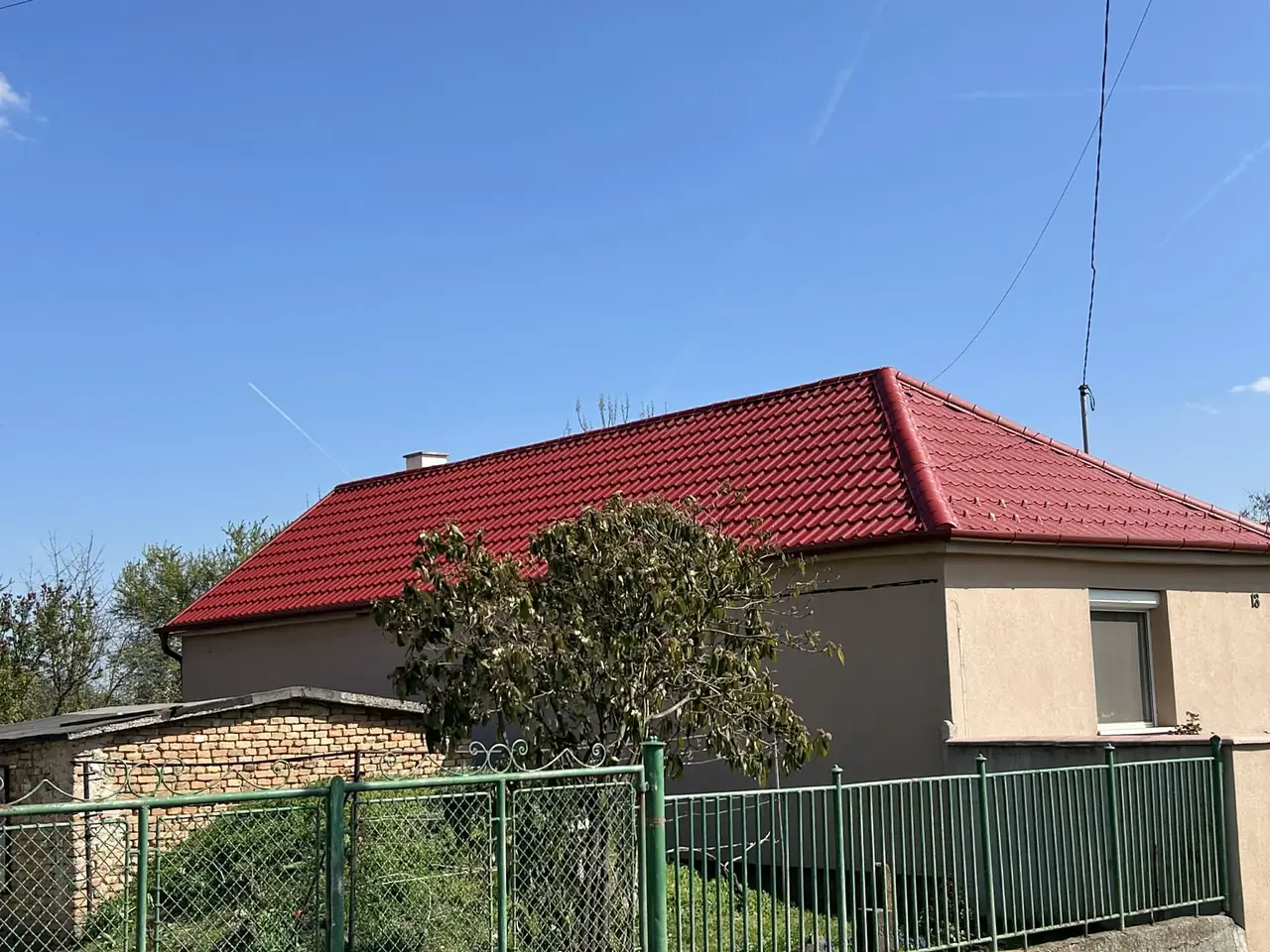 Piros cserepeslemez tető hófogókkal, sátortetős ház