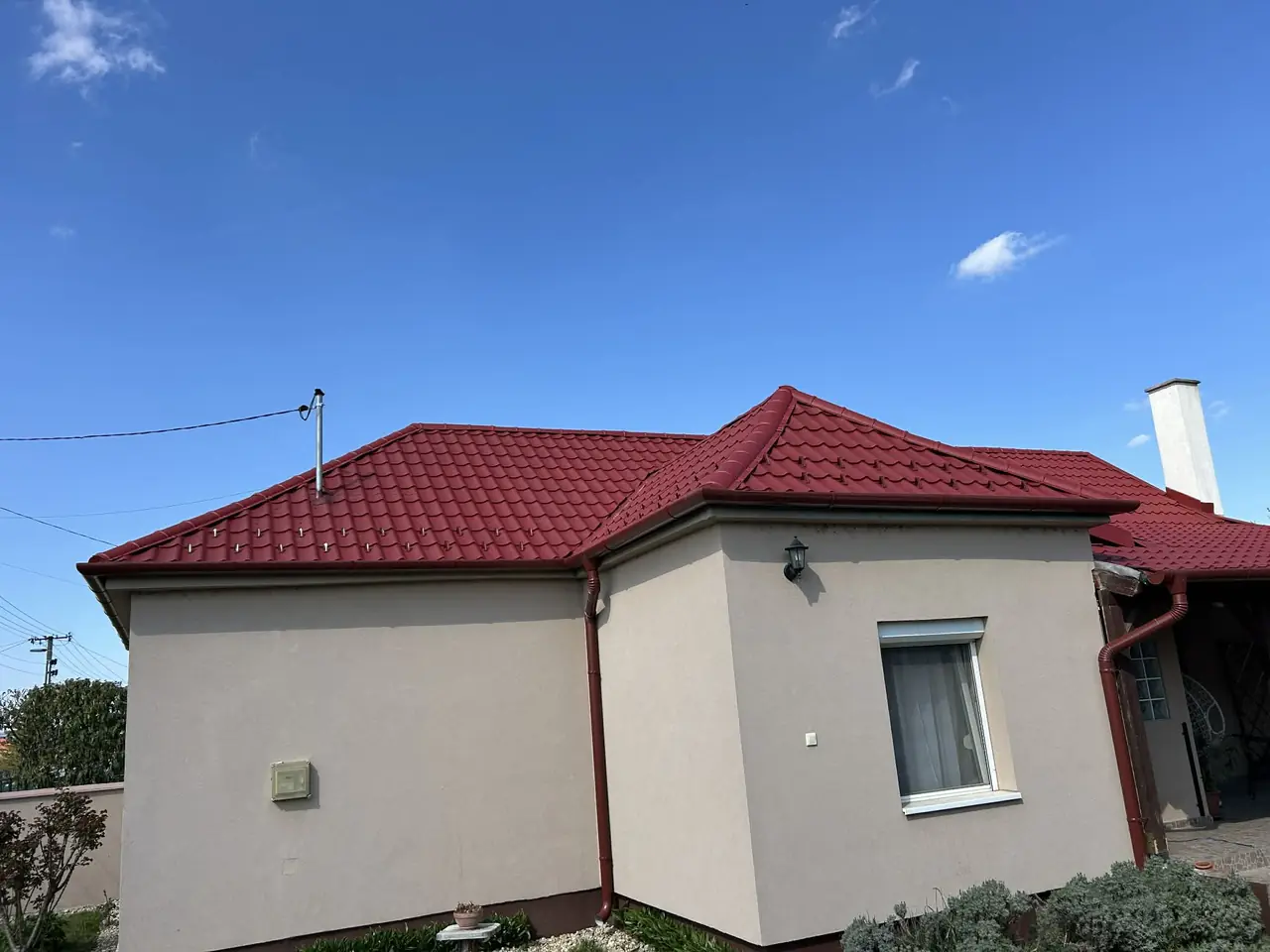 Piros cserepeslemez tető hófogókkal, sátortetős ház